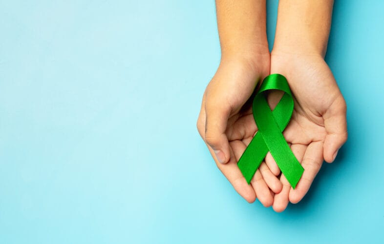 Green ribbon in hands on blue background