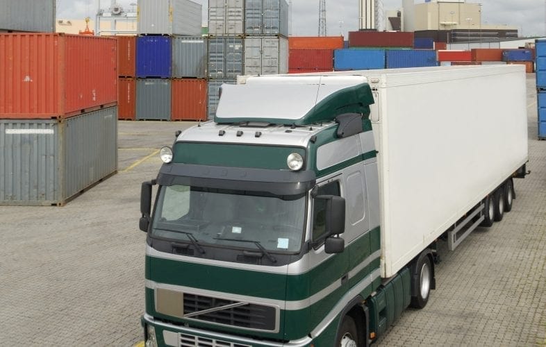 White and green lorry parked in a container port